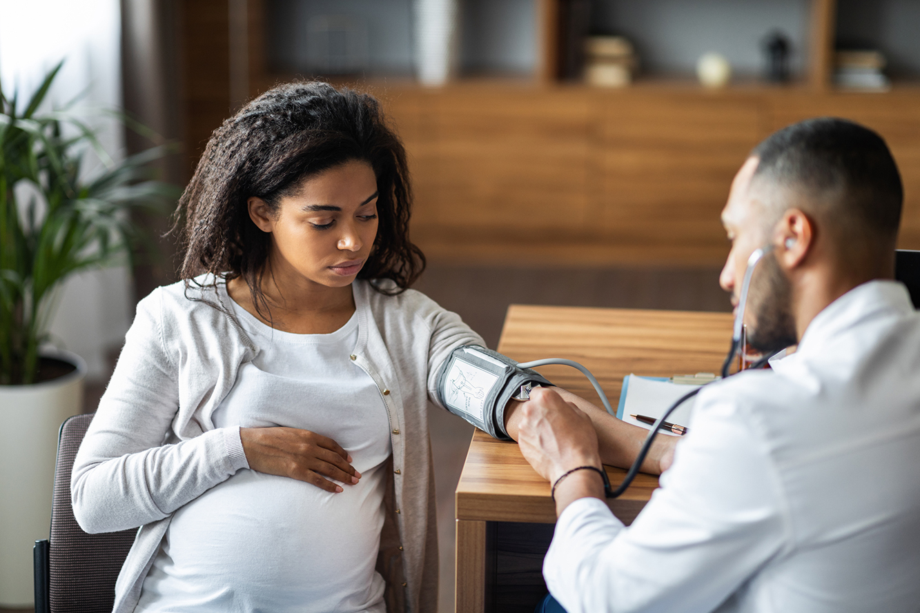 Pregnant person has blood pressure checked by doctor. 